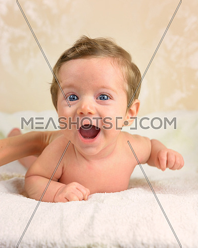 Cute infant boy lie prone and smiling.