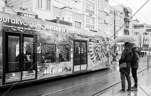 Couple under the rain in front of a tram