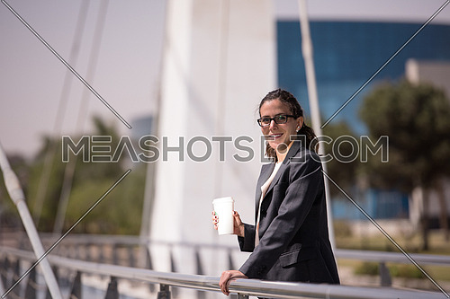 young business woman drinking fresh  morning coffee while walking across modern bridge to shes job