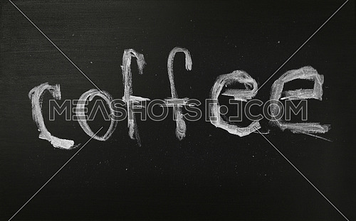 Close up white chalk COFFEE word over hand written over background of black chalkboard menu