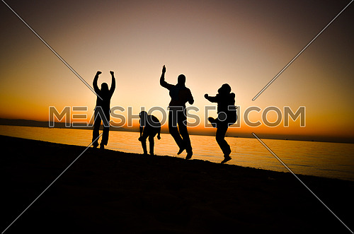 four friends having fun at the beach by sunset