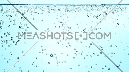 Extreme close up full frame background of pure clear sparkling water with gas in glass, low angle side view, slow motion