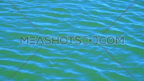 Close up background of vivid teal blue sea ripples running on water surface, high angle view