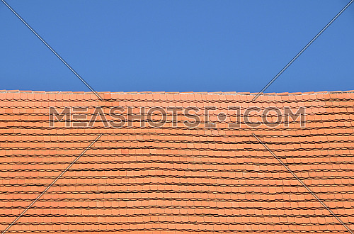 Traditional red brown ceramic roof tiles pattern over background of clear blue sky, close up, low angle side view