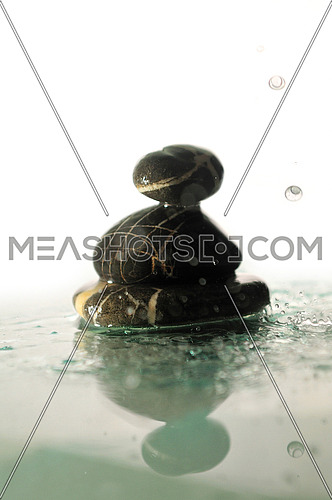 isolated zen stones in perfect harmony with falling and splashing water dropsisolated wet zen stones with splashing  water drops  representing concept of natural balance and perfect harmony