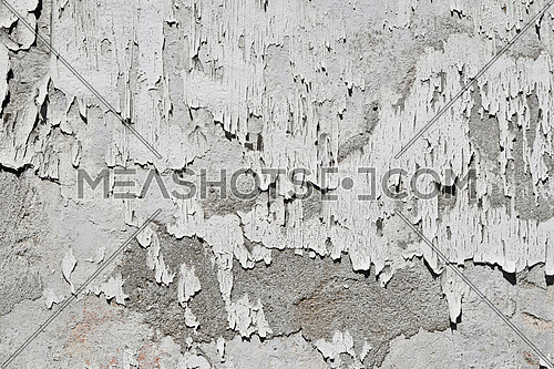 Vintage flakes of old faded white paint over abandoned grey concrete wall