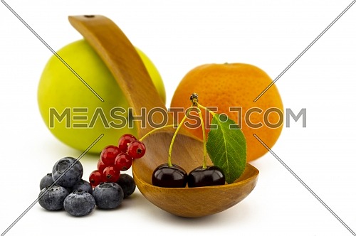 Fresh seasonal fruit still life with assorted berries including blueberries, cherries and red currants on wooden spoons with apple and orange on a white background with copyspace