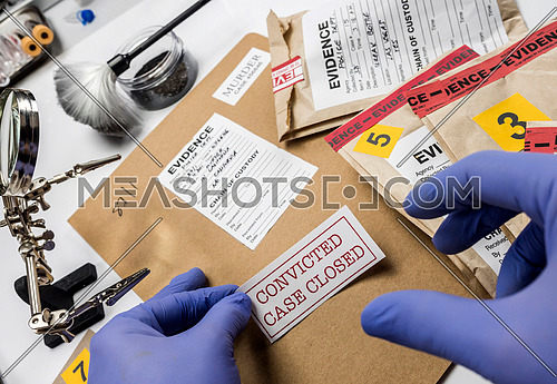 Police expert pastes sticker on dossier closed of murder in the laboratory scientist