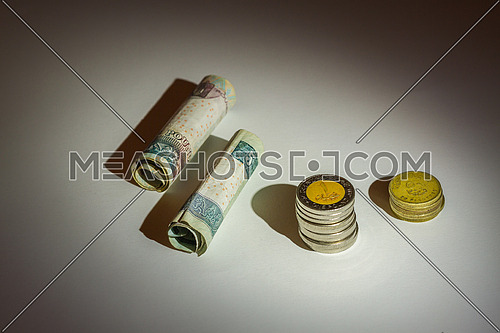 Egyptian Money rolled banknotes and coins on a grey table top under spotlight