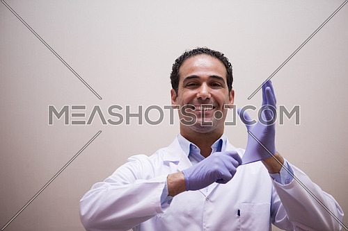 Portrait of a young middle eastern doctor with gloves on his hands with a smile on his face