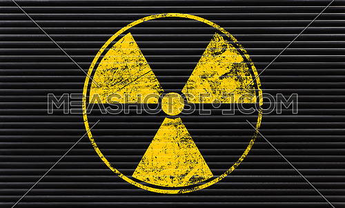 Yellow radioactive hazard warning sign painted over grunge black metal wall background with copy space