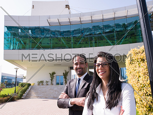 confident young business couple looking in future and standing in front of modern corporate building