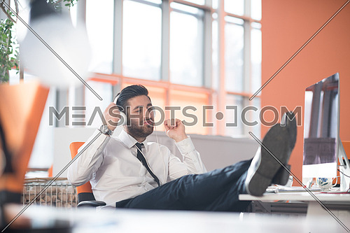 happy young arabian  business man with beard  listening music on headphones at modern startup office