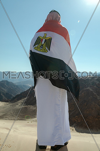 Bedouin man holding Egyptian Flag in Sinai Trail from Ain Hodouda by day.