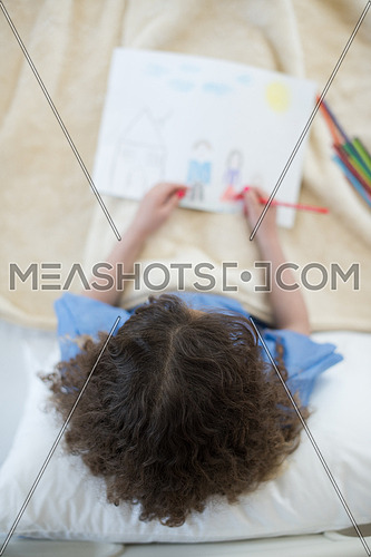 top view of little middle eastern girl painting home and family at hospital bed