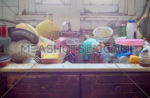 Pile of abandoned dirty utensils in a kitchen washbasin