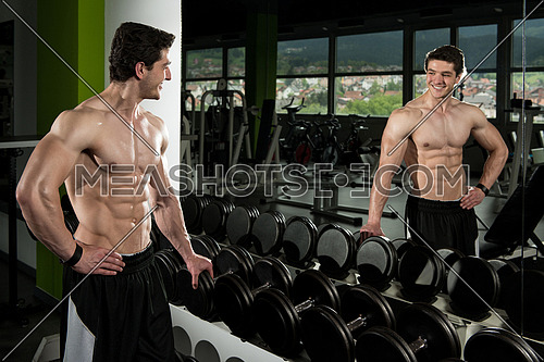 Young Man Standing Strong Next To The Mirror And Flexing Muscles - Muscular Athletic Bodybuilder Fitness Model Posing After Exercises