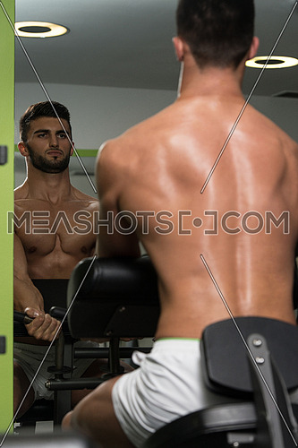 Young Healthy Arabic Man Working Out Biceps - Machine Concentration Curls