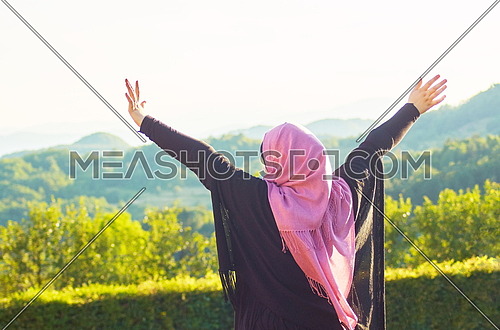 Happy muslim young woman with hijab relaxing outdoor with hands up in the air