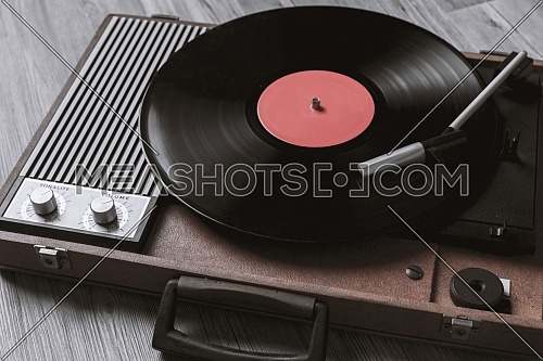 Turntable vinyl record player on the background of their gray wooden boards. Needle on a vinyl record. Black vinyl record,Sound technology for DJ to mix & play music.