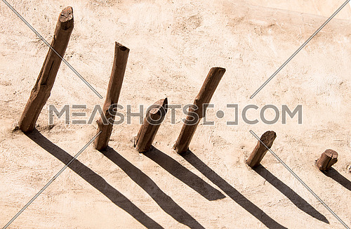 abstract wooden pillers coming out of a concreat wall