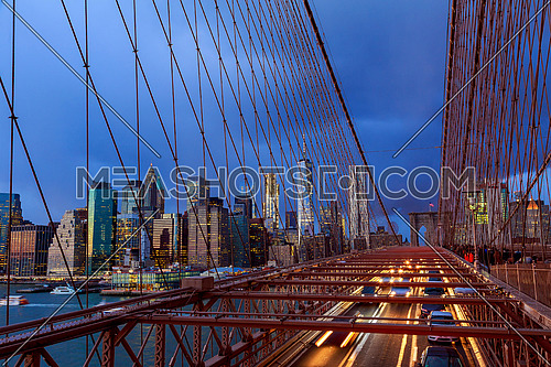 Manhattan skyline from the Brooklyn bridge at dusk with cars trail.