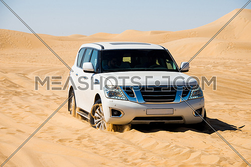 a white SUV stuck in the desert sand