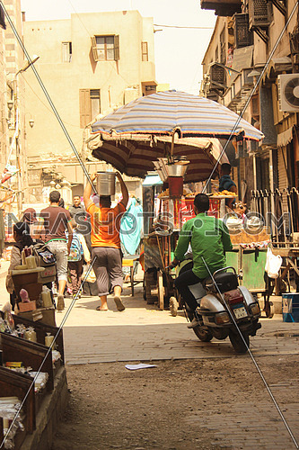 The famous Al Moez street in old Cairo, EGYPT
showing people walking in their busy lives and a man on a scooter   
