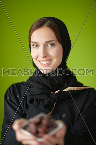 Young muslim girl wearing traditional muslim clothes holding dried dates. Arab girl representing iftar time, holy fasting month, Ramadan Kareem