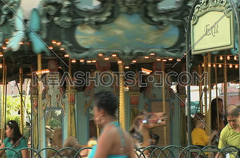 Medium shot for for Carousel spinning while adults and kids having fun in New York city at day.