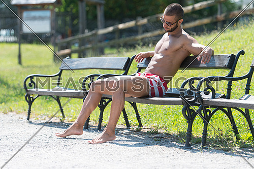Smiling Athlete With Naked Torso Sitting And Resting On Bench