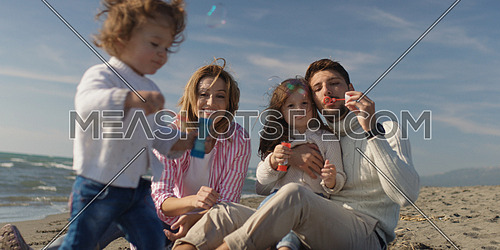 Family with kids resting and having fun at beach during autumn day