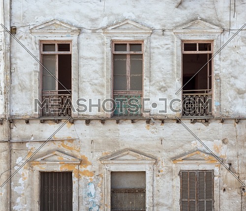 Aged abandoned retro vintage grunge house facade with broken windows and weathered shutters