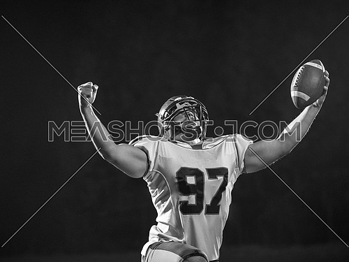 american football player celebrating after scoring a touchdown on field at night