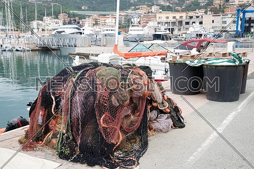 Fishing nets stacked on the waterfront after fishing day,quayside of the port of Varazze, Liguria Italy.