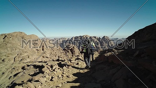 Follow shot for two male tourists exploring Sinai Mountain at day.