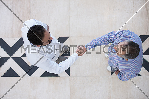 top view of smiling middle eastern doctor at the clinic giving an handshake to his patient, healthcare and professionalism concept