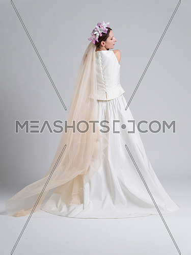 Rear view of a beautiful young bride in a wedding dress isolated on a white background