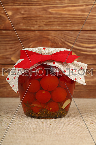 Jar of pickled small red cherry tomatoes on table