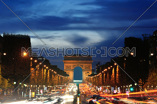 Beautiful night view with car traffic and rush at eavning of the Arc de Triomphe, Paris, France.