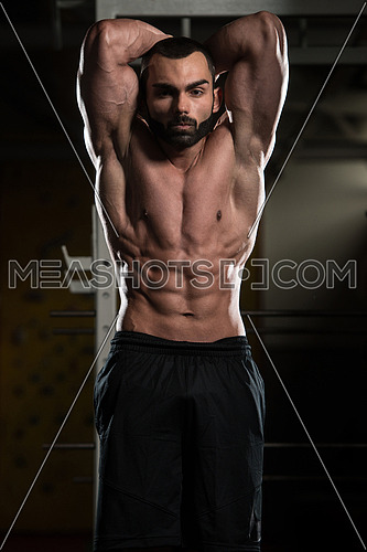 Young Man Standing Strong In The Gym And Flexing Muscles - Muscular Athletic Bodybuilder Fitness Model Posing Showing Abs After Exercises