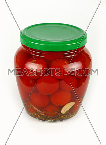 Close up of one glass jar of pickled small red cherry tomatoes with green lid over white background, high angle view