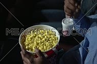 Close Up - high angel for popcorn container while male hand picking up popcorn at movie theatre.