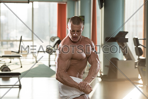 Serious Man Standing In The Gym And Flexing Muscles