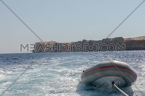 Close shot for Inflatable boat (Zodiac) hanged to backside boat at day.