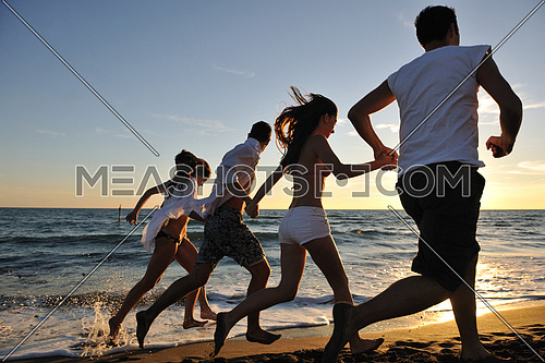 happy young people group have fun white running and jumping on beacz at sunset time