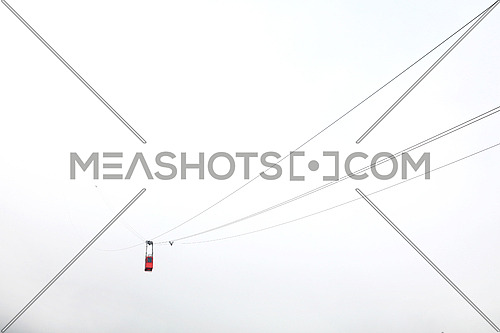 Red mountain cableway car lift lost in clouds and fog, low angle view