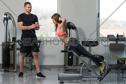 Personal Trainer Working With A Young Woman At The Gym Writing Notes On A Clipboard In A Health And Fitness Concept