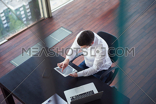 top view of happy young business man,  work tablet and laptop and relax at modern bright office interior, successful hipster with beard at workplace