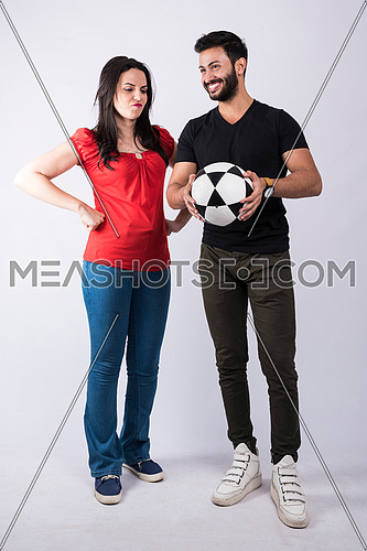 young couple standing and cheering on white background, while both of them having fun with a ball